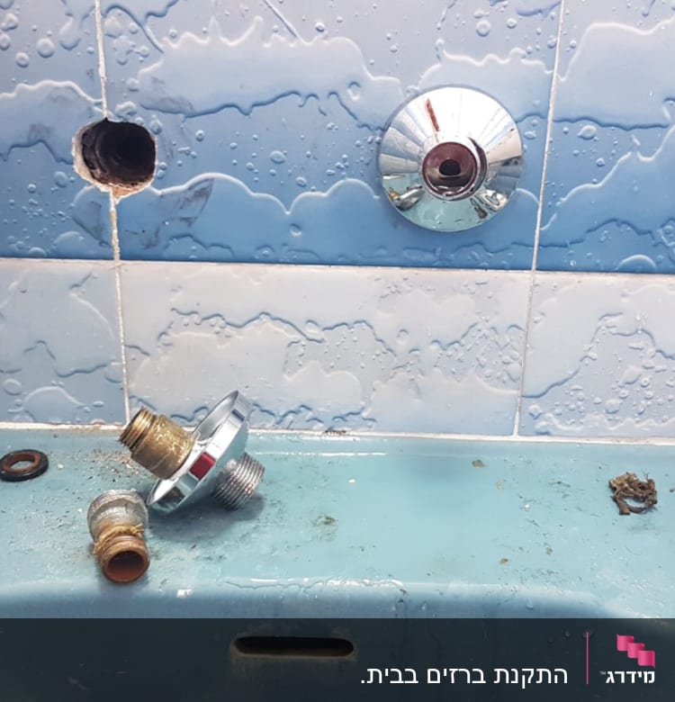 חלקי ברז מפורקים על כיור בחדר אמבטיה